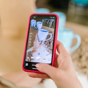 A person capturing a picture of a cup on their phone.